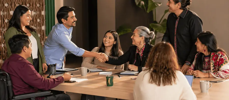 Personas reunidas en una mesa de trabajo se dan la mano